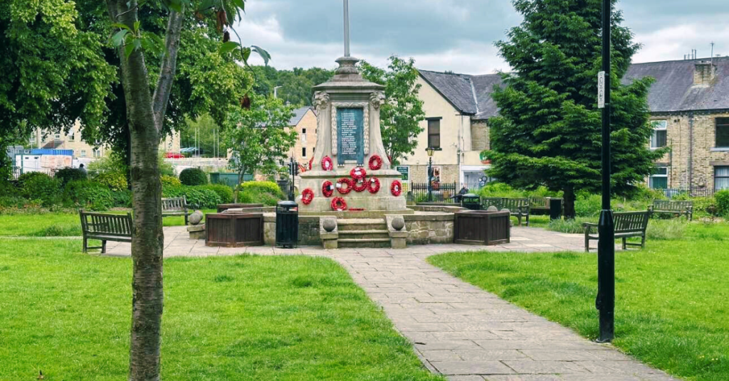 View of Bailiff Bridge Memorial Gardens featuring a cenotaph surrounded by red poppies in remembrance.