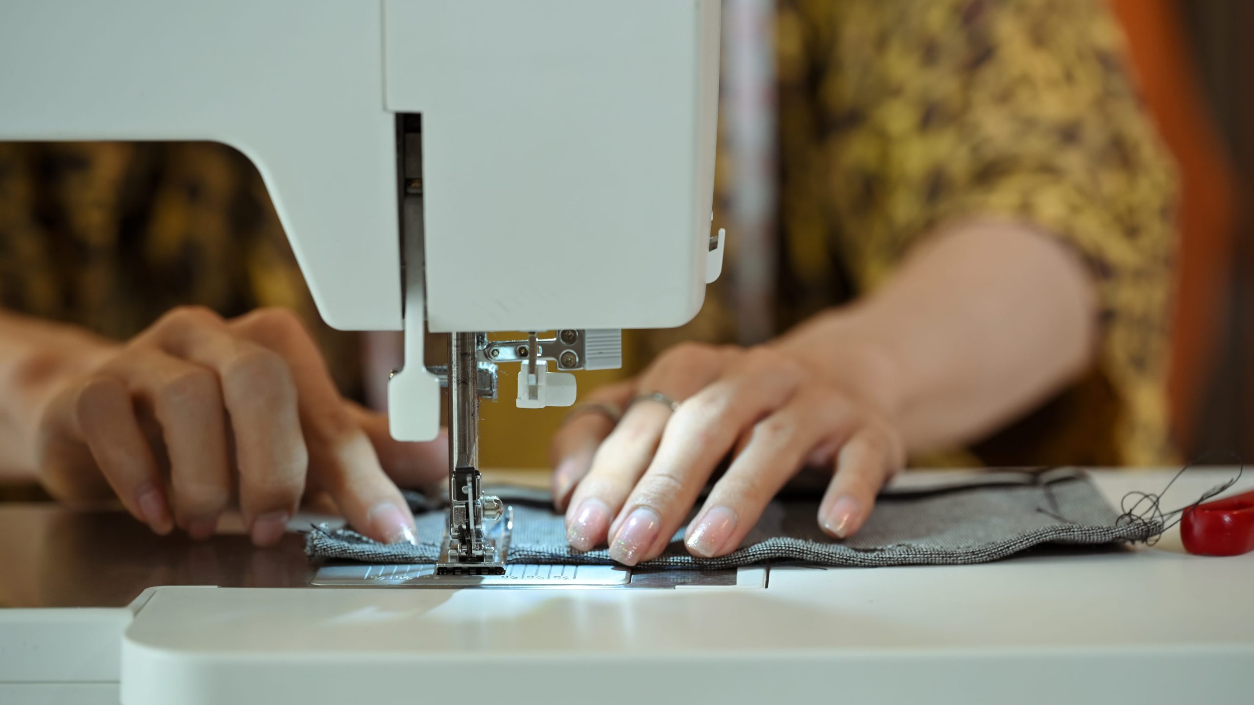 Close up of fashion designer or tailor hands sewing fabric on a sewing machine.